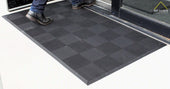 Man steps on heavy-duty anti-slip rubber entrance mat outside doorway.
